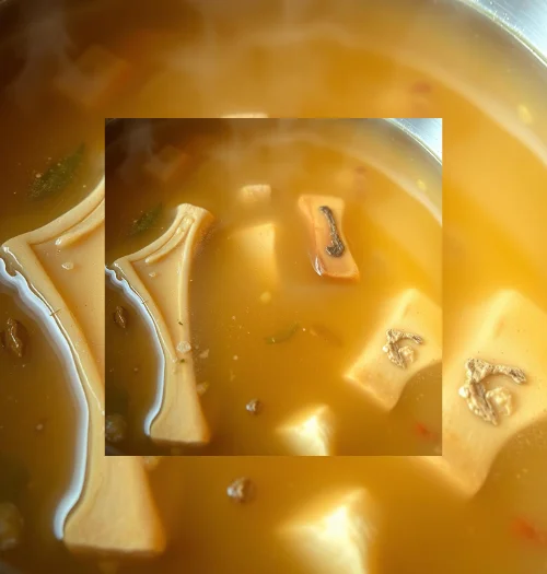 Clear golden bone broth simmering with herbs in a stockpot